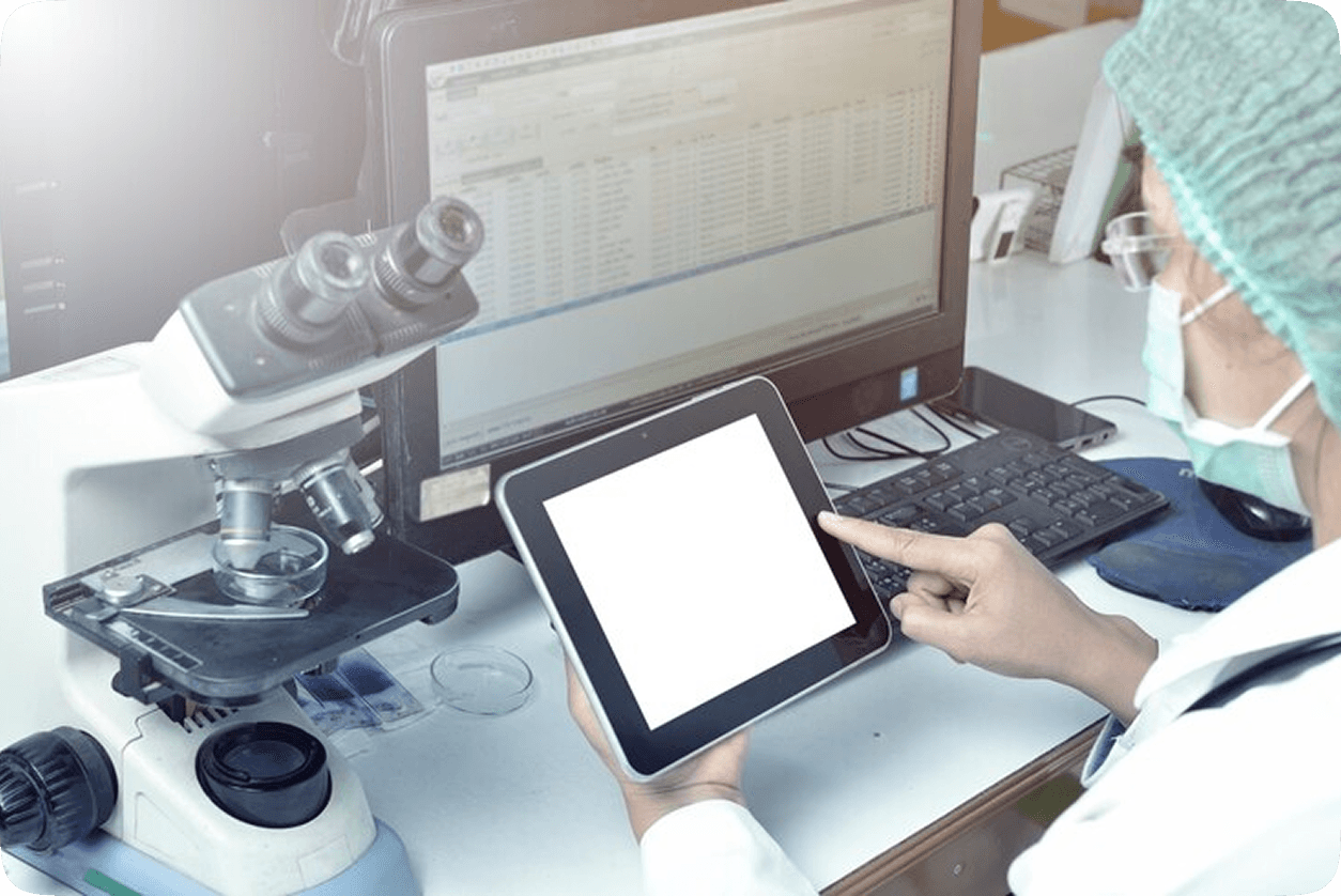Person operating LIMS system on a tablet next to microscope